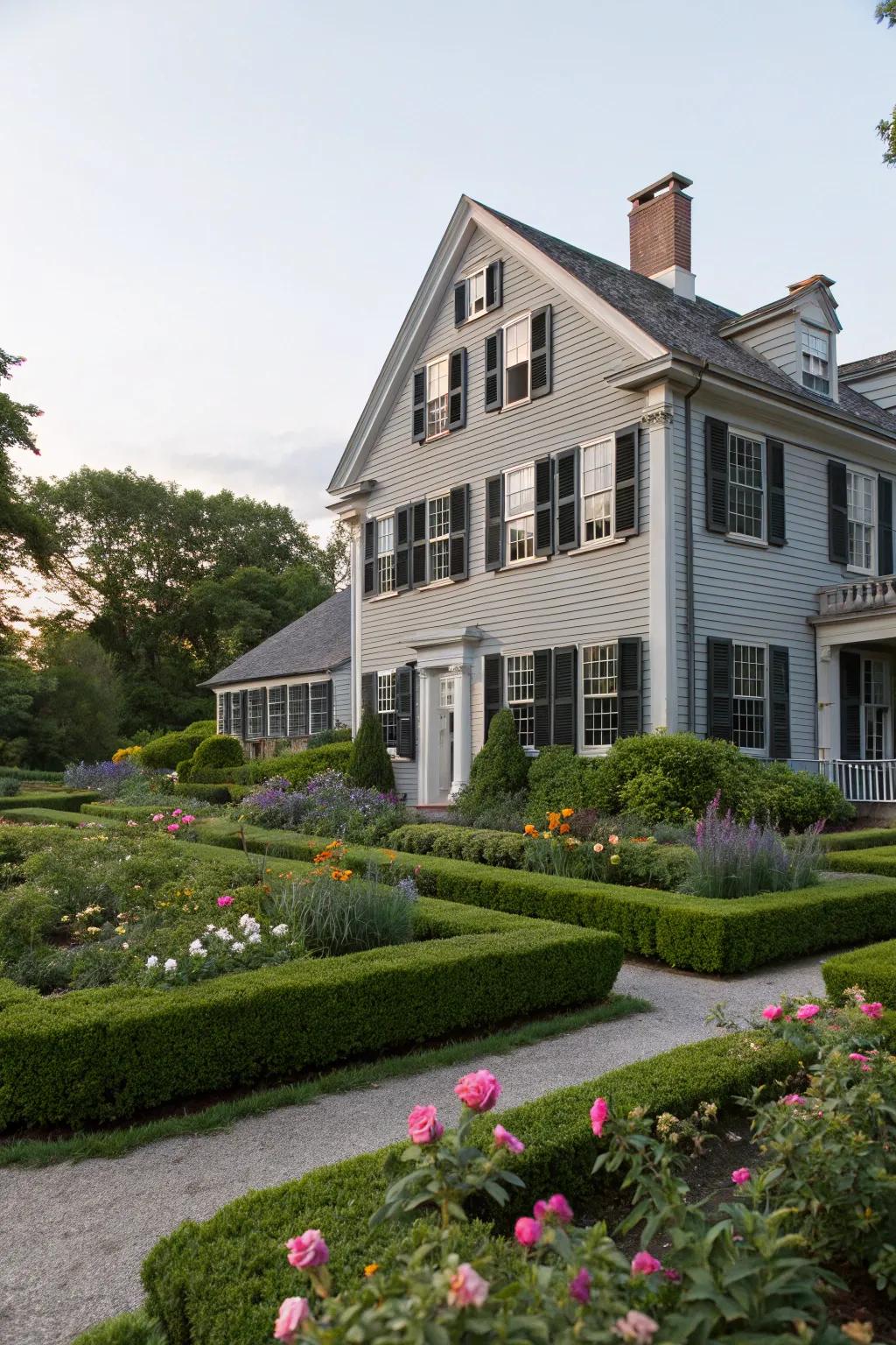 A classic house with a grey exterior and black shutters, exuding elegance in a garden setting.