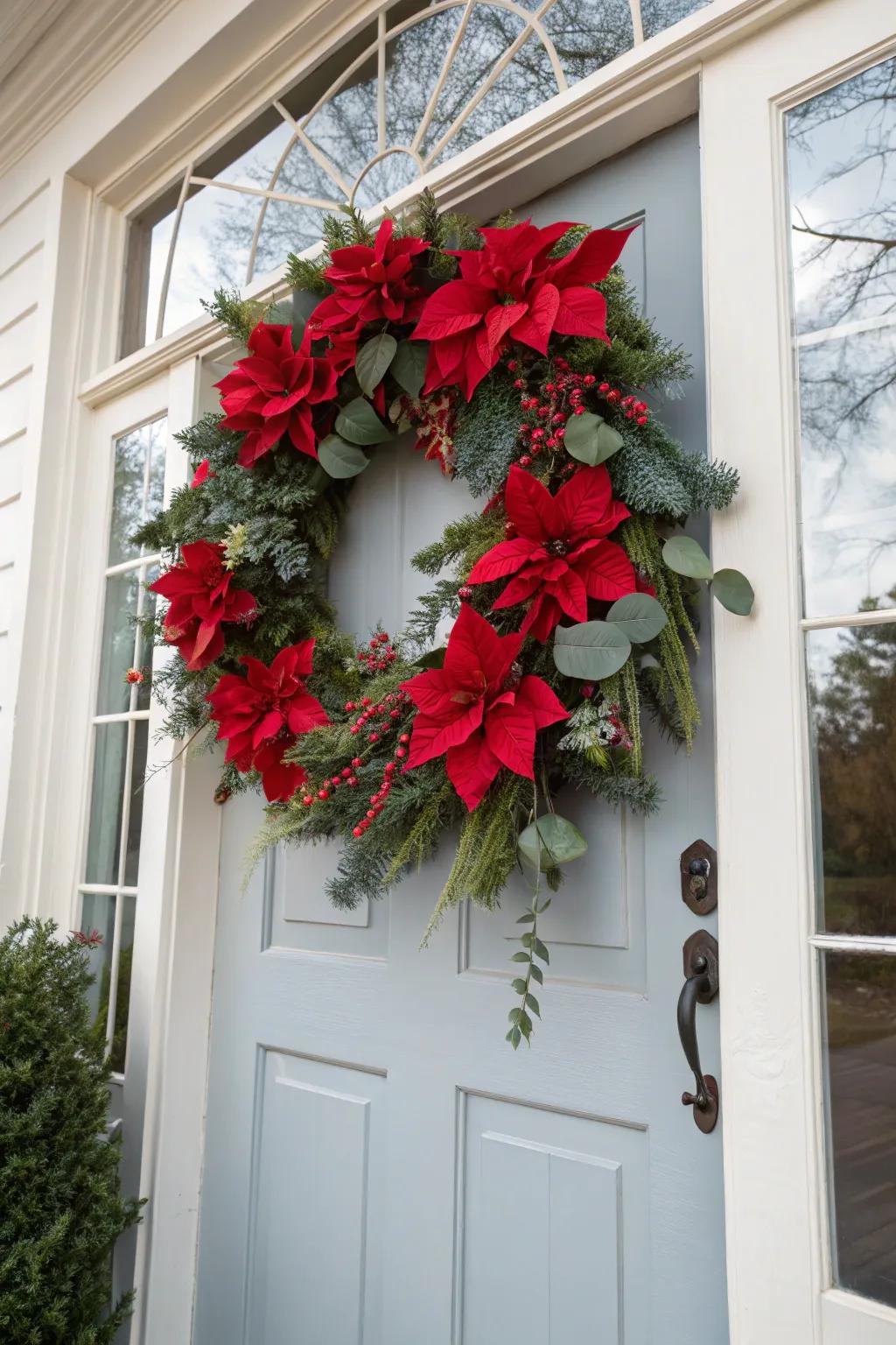 An elegant poinsettia and eucalyptus wreath on a white door.